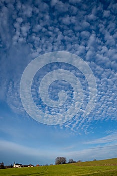 Deep blue sky with cumulus clouds over Bavarian village illuminated by the sun in winter