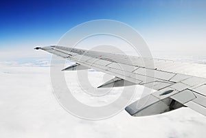 Deep blue sky, white clouds and airplane wing