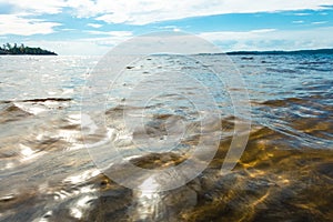 Deep cold blue water of Ladoga lake with sun light reflections under blue cloudy sky