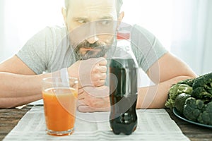 Deep confusing man sitting and looking at cola.