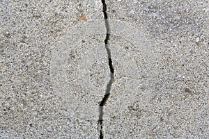 Deep crack in an old brick wall with damaged plaster