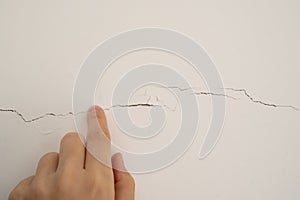 Deep crack on the white wall, which symbolizes the passage of time, wear and tear, aging