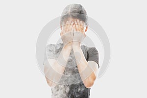 Deep despair. Young dark hair woman close her face with hands isolated over white background with clouds of smoke