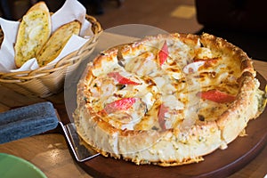 Deep dish seafood pizza Chicago style on the table with garlic bread on the side