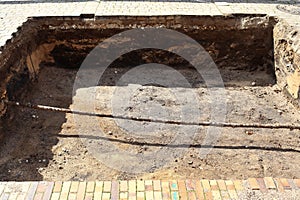 Deep excavation pit revealing underground utility pipe