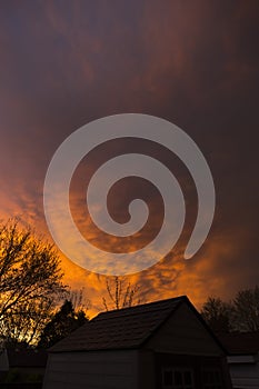 Deep fiery red sunset and stormy clouds over neighborhood houses