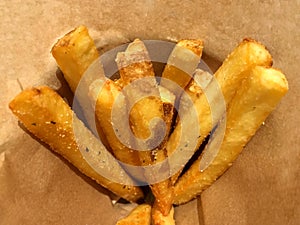 Deep fired potato stick french fries inside brown paper package