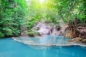 Deep forest waterfall at Erawan waterfall, beautiful waterfall with sunlight rays in deep forest, Erawan National Park