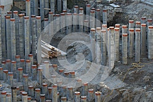 Deep foundation concrete pilings partially hammered into the ground