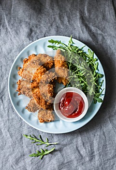 Deep-fried bread crumbs fried chicken fillet with ketchup and salad - delicious appetizer, tapas on grey background