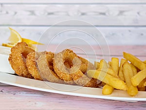 DEEP FRIED CALAMARI SQUID RINGS With French Fries served in dish isolated on table closeup top view of grilled seafood