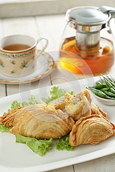 Deep fried chicken puffs in ceramic plate and accompany by a cup of tea. Selective focus.