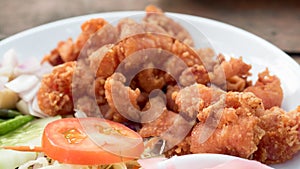 Deep fried chicken tendons on white dish close up with wooden ba