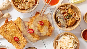 Deep fried Crispy chicken in breadcrumbs served on white wooden table with salad, spices