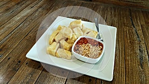 Deep fried crispy tofu in small bite serving with sweet dipping sauce with grounded peanut and chili powder