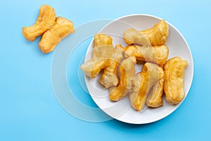 Deep-fried dough stick, chinese bread stick on white dish. Blue background