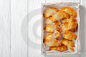 Deep fried empanadas on a wooden tray