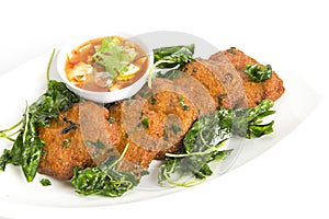 Deep fried fish cake serve with fried basil leaves  eat with sweet cucumber sauce