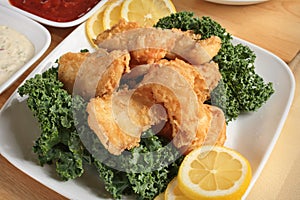 Deep fried fish strips on garnished plate with lemon