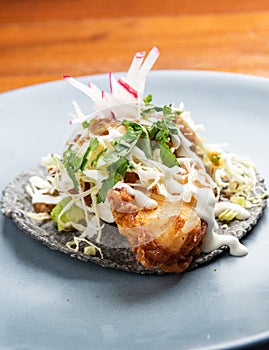 Deep fried fish taco in a black corn torilla