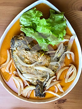 deep-fried flounder with onions and vegetables in Asian sauce on a plate.