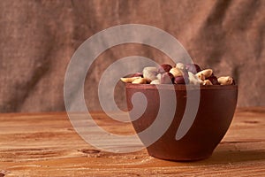 Deep fried peanuts in clay bowl over rustic wicker background. Selective focus