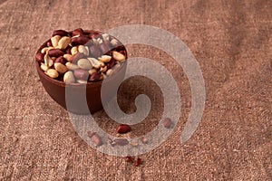 Deep fried peanuts in clay bowl over rustic wicker background. Selective focus