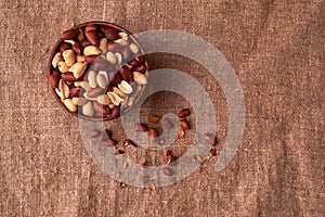 Deep fried peanuts in clay bowl over rustic wicker background. Selective focus