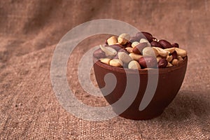 Deep fried peanuts in clay bowl over rustic wicker background. Selective focus