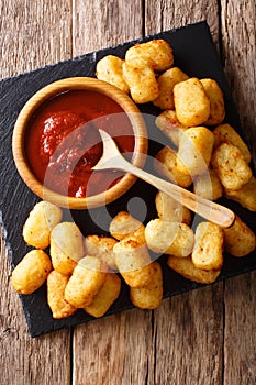 Deep-fried potato tater tots and ketchup close-up. Vertical top