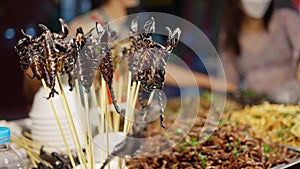 Deep fried scorpions, a woman sells bugs in night market at Bangkok chinatown