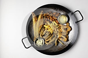 Deep fried set made from french fries, onion rings, big and small fried fish served in a wok over white background.