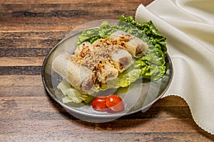 Deep fried Shrimp Spring Rolls with lettuce leaf and tomato served in dish isolated on wooden table top view of hong kong fast