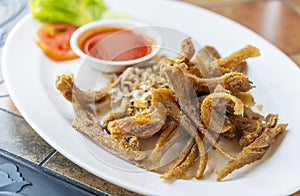 Deep-fried small fishes or Sillago fish with garlics. Crispy fried Sillago in white plate on table in resturant. Close up Thailand