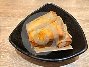 Deep Fried Spring Rolls serving on black plate, classic snack food made with ground pork, matchstick cut carrots, sliced cabbage