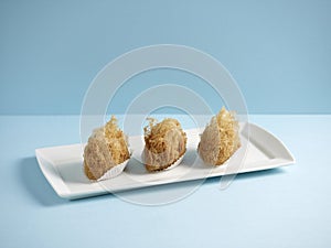 deep-fried taro puff with diced chicken served in a dish isolated on wooden board side view on grey background