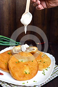 Deep frying pies with meat on a white plate with sour cream photo