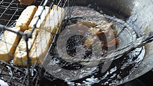 A deep frying tofu in boiling oil.