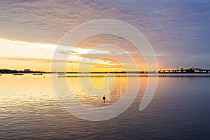 Deep golden sunrise over calm lake, silhouette of bird swimming