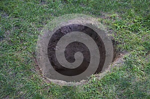 Deep hole in ground or lawn photo