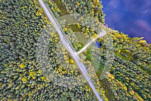 Deep lake near highway among yellow forests in autumn