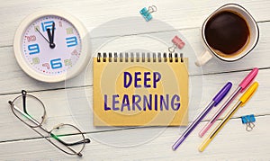 DEEP LEARNING - an inscription on a notebook on a table with a clock and office supplies