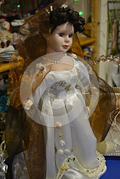 It is deep look of a doll in white dress and brown veil