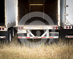 Deep look in to an empty tractor trailer as the grass grows in the deserted truck yard