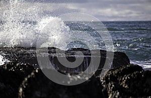 Deep ocean wave crashing on rocks