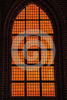 Deep orange light coming from a church is Gothic window conveys a diabolic, hellish and evil feeling with wicked and cruel concept