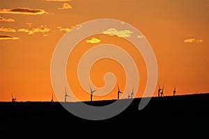 Deep orange skies behind silhouetted windmills