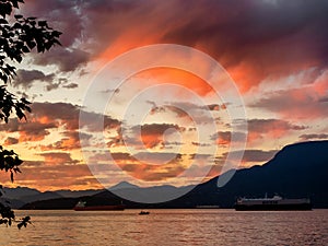 Deep orange and yellow clouds create drama as the sun sets over parts of the English Bay harbor area of Vancouver