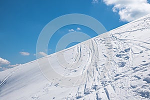 Deep powder snow piste with ski tracks, against blue sky photo