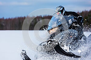 In deep powder snowdrift snowmobile rider driving fast